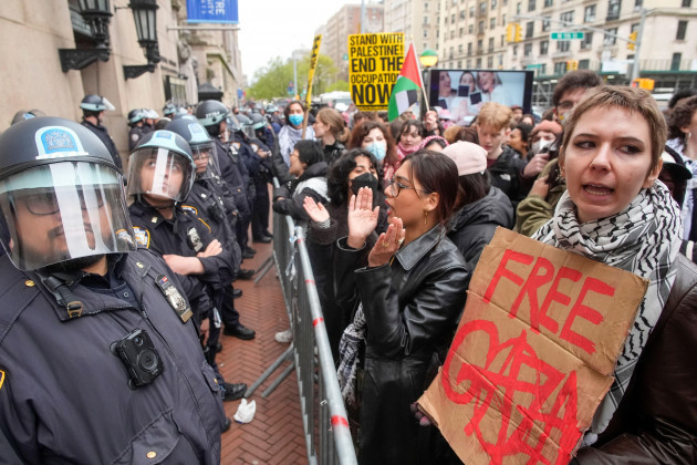 file-police-in-riot-gear-stand-guard-as-demonstrators-chant-slogans-outside-the-columbia-university-campus-thursday-april-18-2024-in-new-york-u-s-colleges-and-universities-are-preparing-for-en