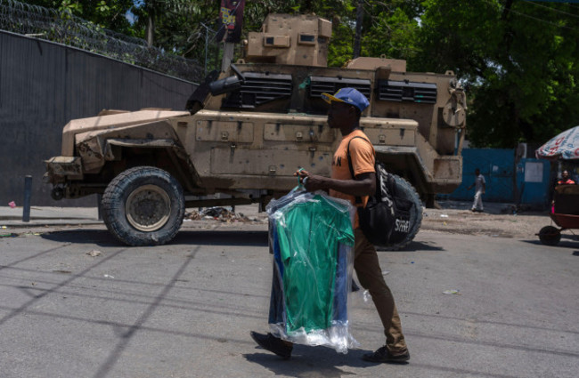 a-man-carries-dry-cleaning-past-an-armored-police-vehicle-in-port-au-prince-haiti-sunday-april-28-2024-ap-photoramon-espinosa