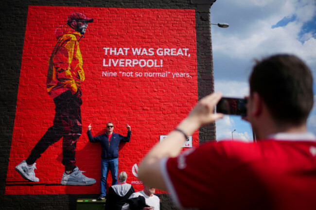 a-fan-poses-for-photos-next-to-a-mural-with-the-image-of-liverpools-manager-jurgen-klopp-prior-to-the-english-premier-league-soccer-match-between-liverpool-and-tottenham-hotspur-at-anfield-stadium-in