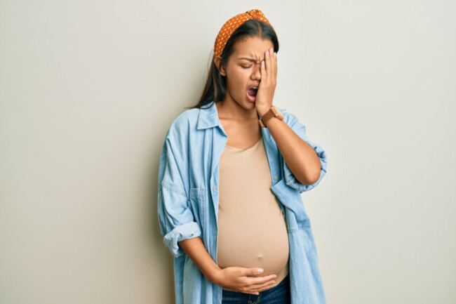 beautifulhispanicwomanexpectingababytouchingpregnantbellyyawning