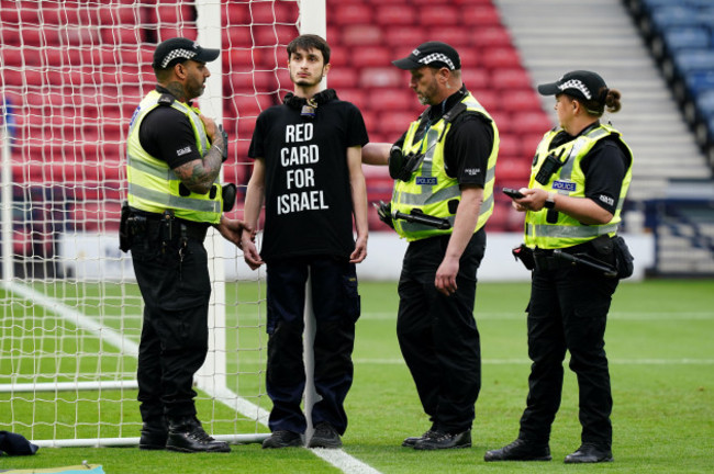 police-speak-to-a-protestor-wearing-a-red-card-for-israel-t-shirt-after-they-chained-themselves-to-a-goalpost-ahead-of-the-uefa-womens-euro-2025-qualifying-league-b-group-b2-match-at-hampden-park