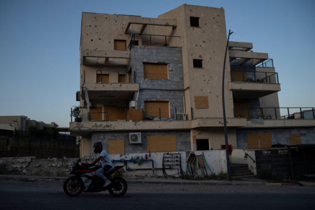 a-man-drives-his-motorcycle-past-a-damaged-building-from-previous-shelling-attacks-from-lebanon-in-kiryat-shmona-northern-israel-wednesday-june-19-2024-hezbollah-began-attacking-israel-almost-i