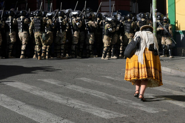 a-woman-walks-by-military-police-in-plaza-murillo-in-la-paz-bolivia-wednesday-june-26-2024-armored-vehicles-rammed-into-the-doors-of-bolivias-government-palace-located-in-plaza-murillo-on-wedn
