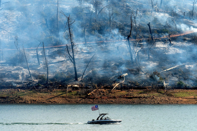 a-boat-crosses-lake-oroville-with-a-smoldering-hillside-behind-as-the-thompson-fire-burns-in-oroville-calif-on-wednesday-july-3-2024-an-extended-heatwave-blanketing-northern-california-has-resul