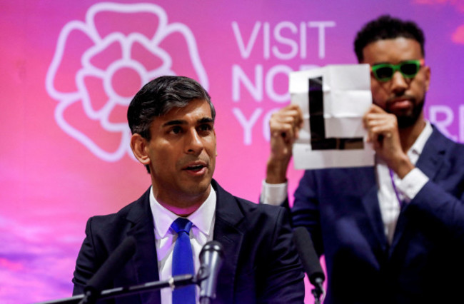 independent-candidate-niko-omilana-holds-an-l-behind-prime-minister-rishi-sunak-during-his-speech-at-northallerton-leisure-centre-in-northallerton-north-yorkshire-after-holding-his-seat-in-the-ric