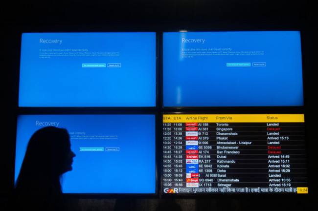 new-delhi-delhi-india-19th-july-2024-people-move-past-screens-displaying-error-messages-amid-global-microsoft-outage-at-the-indira-gandhi-international-igi-airport-in-new-delhi-india-on-july