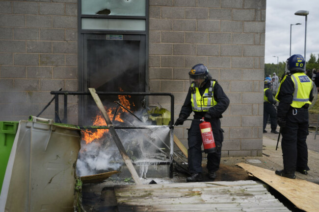 a-fire-is-extinguished-by-police-officers-as-trouble-flares-during-an-anti-immigration-protest-outside-the-holiday-inn-express-in-rotherham-south-yorkshire-picture-date-sunday-august-4-2024