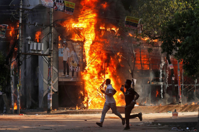 men-run-past-a-shopping-center-which-was-set-on-fire-by-protesters-during-a-rally-against-prime-minister-sheikh-hasina-and-her-government-demanding-justice-for-the-victims-killed-in-the-recent-country