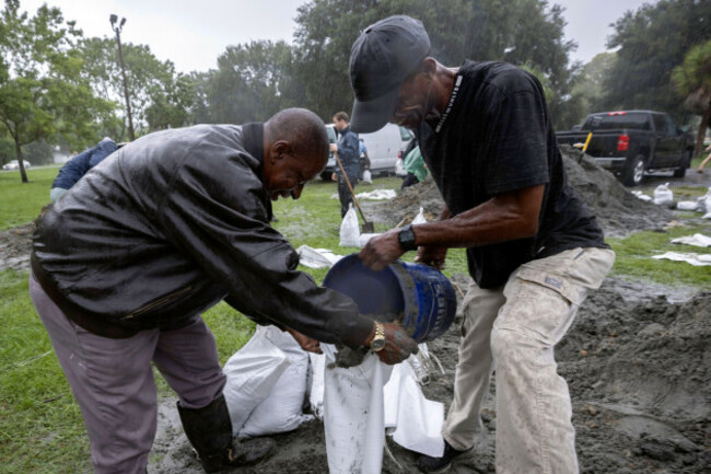 hershey-stepherson-left-and-bryan-burc-right-use-a-five-gallon-bucket-to-fill-a-sandbag-while-preparing-for-hurricane-debby-monday-aug-5-2024-in-savannah-ga-debby-reached-the-big-bend-coast