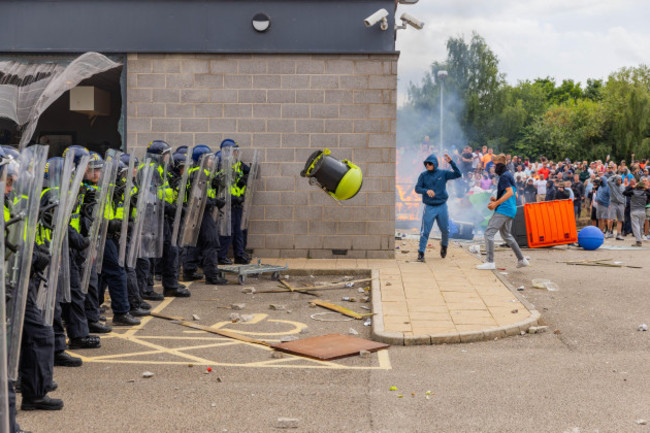 rotherham-uk-04-aug-2024-a-fire-is-started-as-a-rioter-throws-furniture-at-police-lines-with-hundreds-of-police-and-protestors-clashing-outside-a-holiday-inn-express-on-manvers-way-rotherham-the