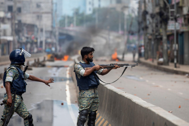 a-policeman-aims-his-weapon-at-protesters-during-a-curfew-imposed-following-violence-during-protests-against-prime-minister-sheikh-hasina-and-her-government-in-dhaka-bangladesh-monday-aug-5-2024