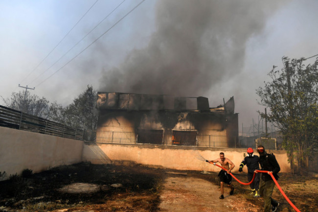 two-men-and-a-volunteer-firefighter-try-to-extinguish-the-flames-at-a-burning-business-during-a-fire-in-northern-athens-monday-aug-12-2024-as-hundreds-of-firefighters-tackle-a-major-wildfire-ragi