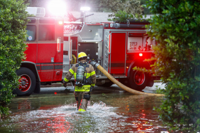 tampa-firefighters-work-to-contain-a-house-fires-while-they-walk-in-a-flooded-street-around-the-sunset-park-neighborhood-after-hurricane-helene-on-friday-sept-27-2024-in-tampa-fla-jefferee-woo