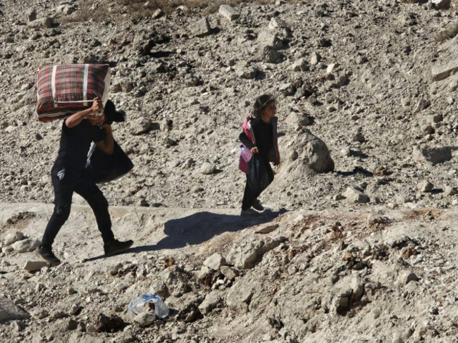 syrians-carry-their-belongings-as-they-cross-on-foot-into-syria-through-a-crater-caused-by-an-israeli-airstrike-to-cut-the-road-between-the-lebanese-and-the-syrian-checkpoints-at-the-masnaa-crossing