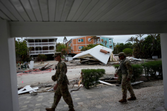 members-of-the-florida-army-national-guard-walk-past-a-destroyed-home-that-was-washed-down-the-block-by-hurricane-helene-as-they-check-for-any-remaining-residents-ahead-of-the-arrival-of-hurricane-mi