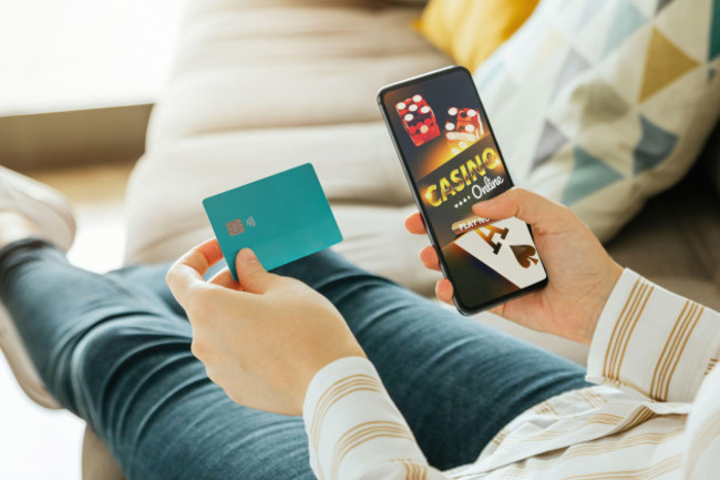 stock-photo-of-a-unrecognizable-woman-going-to-play-online-casino-from-the-couch-and-holding-a-credit-card-to-pay-online-gambling-and-betting-concept