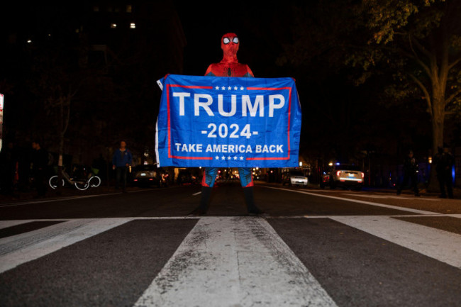 a-person-dressed-as-spiderman-holds-a-banner-with-the-text-trump-2024-take-america-back-in-black-lives-matter-plaza-in-washington-dc-usa-on-tuesday-november-5-2024