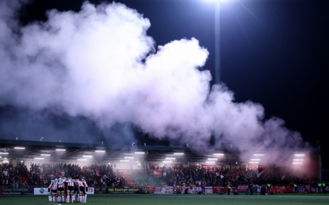 the-derry-city-team-huddle-as-shelbourne-fans-set-off-smoke-in-the-crowd