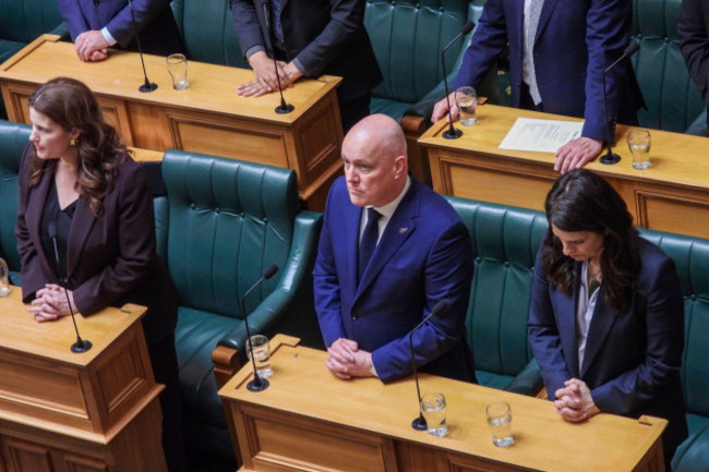 new-zealand-prime-minister-christopher-luxon-center-stands-in-silence-ahead-of-making-a-formal-and-unreserved-apology-in-parliament-for-the-widespread-abuse-torture-and-neglect-of-hundreds-of-tho