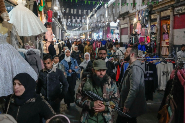 an-armed-opposition-fighter-walks-among-costumers-at-the-al-hamidiyeh-market-inside-the-old-walled-city-of-damascus-syria-tuesday-dec-10-2024-ap-photohussein-malla