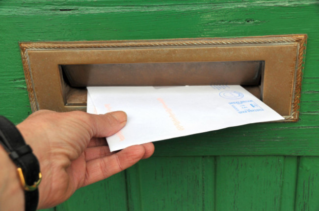 postman-delivering-a-letter-through-a-letter-box-of-a-wooden-front-door