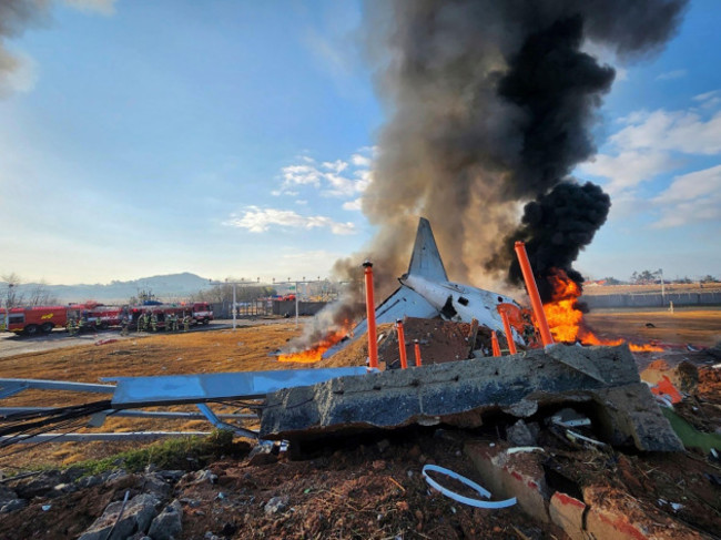 in-this-photo-provided-by-south-koreas-muan-fire-station-a-passenger-plane-is-in-flames-at-the-muan-international-airport-in-muan-south-korea-sunday-dec-29-2024-south-koreas-muan-fire-statio