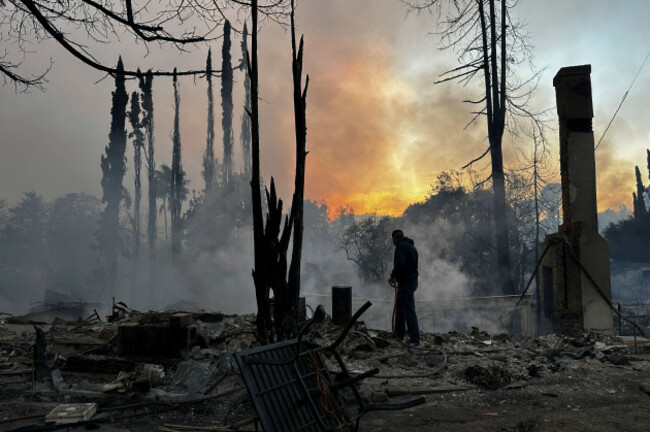 a-resident-hoses-down-hot-spots-in-a-fire-ravaged-property-after-the-palisades-fire-swept-through-in-the-pacific-palisades-neighborhood-of-los-angeles-wednesday-jan-8-2025-ap-photoeugene-garcia