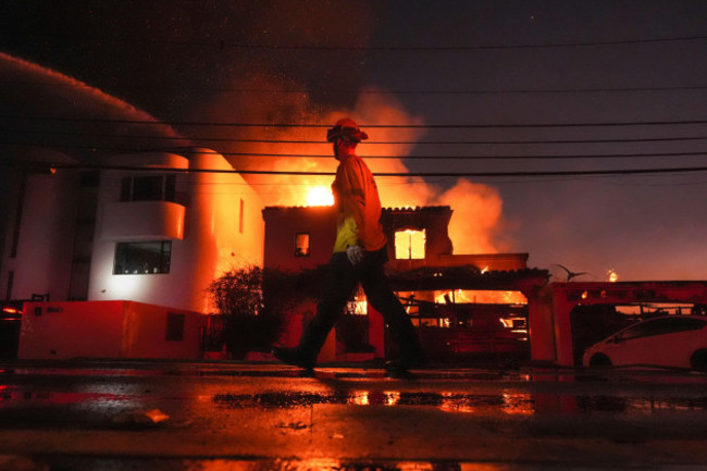 a-firefighter-walks-past-a-burning-structure-as-the-palisades-fire-continues-to-burn-in-the-pacific-palisades-neighborhood-of-los-angeles-wednesday-jan-8-2025-ap-photomark-j-terrill