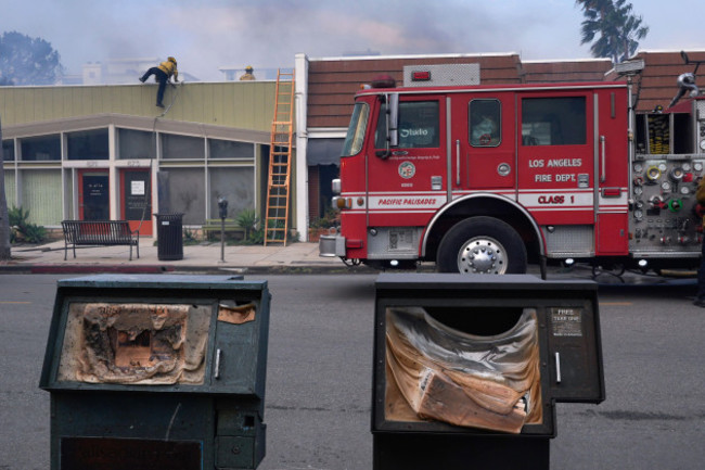 los-angeles-fired-department-fireman-climb-a-building-near-melted-newspaper-boxes-as-the-palisades-fire-ravages-a-neighborhood-amid-high-winds-in-the-pacific-palisades-neighborhood-of-los-angeles-wed