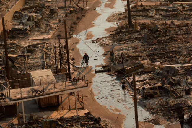 a-person-walks-with-a-bicycle-amid-the-destruction-left-behind-by-the-palisades-fire-in-the-pacific-palisades-neighborhood-of-los-angeles-thursday-jan-9-2025-ap-photojae-c-hong