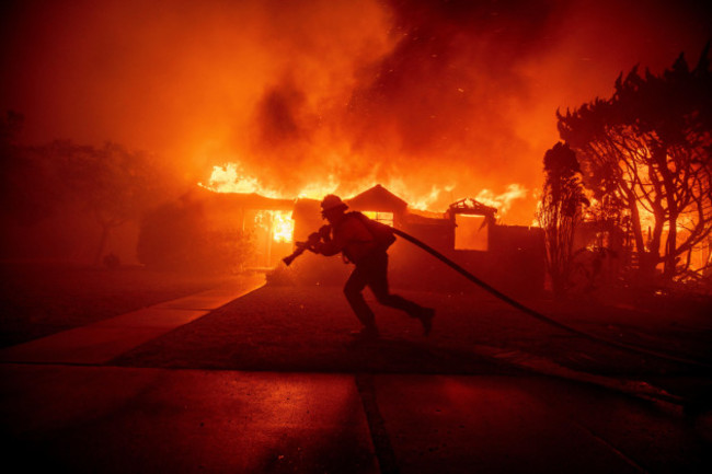 a-firefighter-battles-the-palisades-fire-as-it-burns-a-structure-in-the-pacific-palisades-neighborhood-of-los-angeles-tuesday-jan-7-2025-ap-photoethan-swope