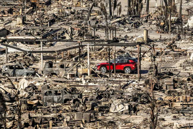 a-car-drives-past-homes-and-vehicles-destroyed-by-the-palisades-fire-at-the-pacific-palisades-bowl-mobile-estates-on-sunday-jan-12-2025-in-los-angeles-ap-photonoah-berger