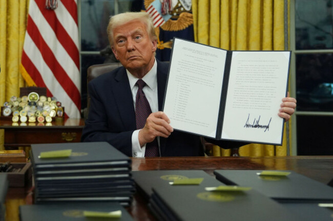 president-donald-trump-holds-up-an-executive-order-commuting-sentences-for-people-convicted-of-jan-6-offenses-in-the-oval-office-of-the-white-house-monday-jan-20-2025-in-washington-ap-photoev