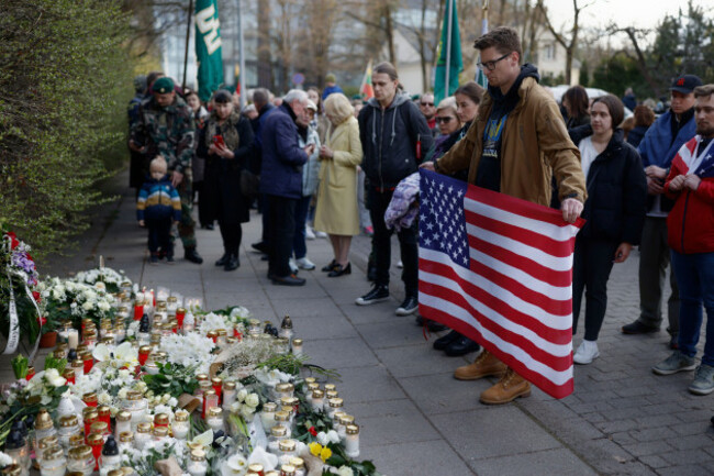 a-man-with-a-u-s-national-flag-and-other-people-stand-as-they-come-to-pay-their-last-respects-in-memory-of-three-u-s-army-soldiers-found-dead-on-monday-at-a-training-range-in-pabrade-near-the-u-s