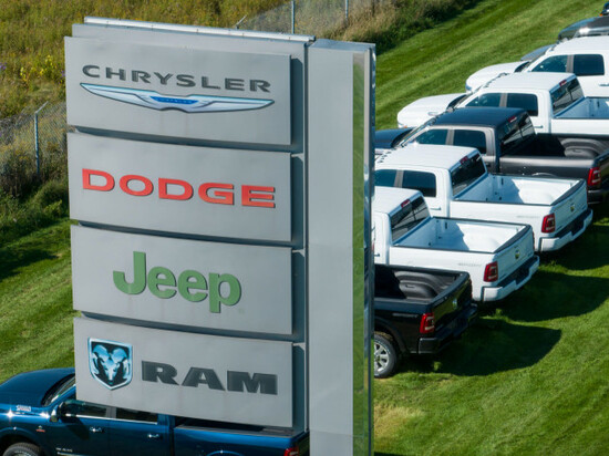 a-sign-with-the-chrysler-dodge-jeep-and-ram-logos-on-into-out-from-a-large-car-dealership-selling-the-popular-stellantis-brands