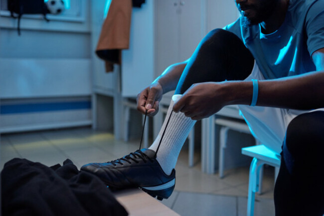 youngafricansoccerplayertyingshoelaceswhilesittinginchanging