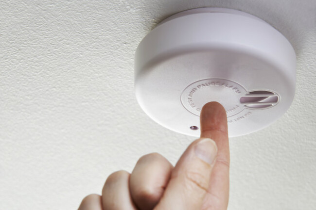 closeupofhandtestingdomesticsmokealarm
