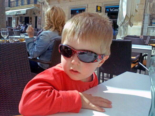 little-boy-with-sunglasses-sitting-in-a-sidewalk-cafe