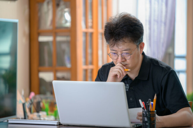 middle-aged-asian-man-working-at-home-telecommuting-concept