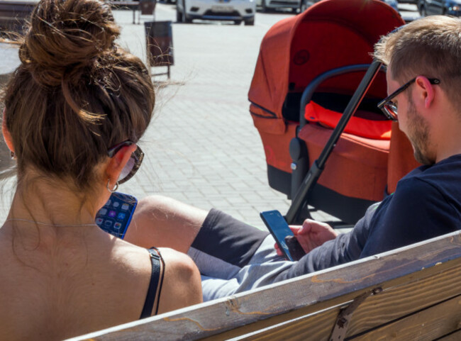 voronezh-russia-june-23-2018-young-parents-sit-on-the-olympic-park-bench-with-phones-in-their-hands