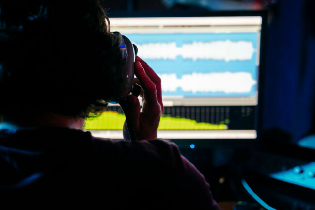 man-holding-headphones-while-using-computer-in-recording-studio-at-home