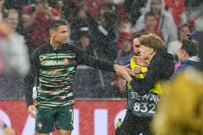 stewards-grab-a-boy-that-invaded-the-pitch-trying-to-get-to-portugals-cristiano-ronaldo-during-warmup-before-the-nations-league-semifinal-soccer-match-between-portugal-and-germany-at-the-munich-footb