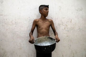 gaza-gaza-palestine-18th-may-2025-a-young-boy-visibly-malnourished-stands-with-a-large-empty-pot-for-food-as-displaced-palestinians-go-to-receive-a-free-meal-at-a-displacement-camp-in-central-ga