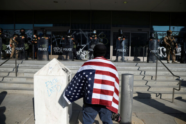 a-protester-draped-in-an-american-flag-stands-in-front-of-the-federal-building-in-los-angeles-during-a-demonstration-in-response-to-a-series-of-united-states-immigration-and-customs-enforcement-ice