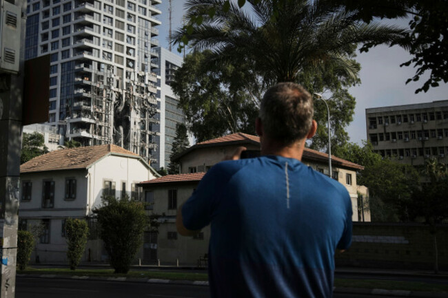a-man-takes-a-photo-of-a-residential-building-that-was-struck-by-a-missile-fired-from-iran-in-tel-aviv-israel-on-saturday-june-14-2025-ap-photoleo-correa