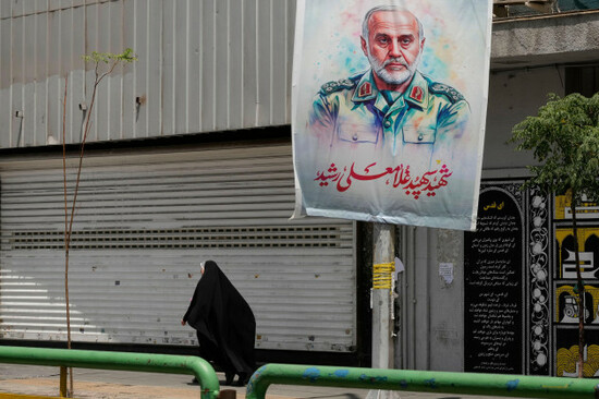 an-iranian-woman-walks-past-a-banner-showing-head-of-the-paramilitary-revolutionary-guards-khatam-al-anbiya-central-headquarters-gen-gholam-ali-rashid-who-was-killed-in-israeli-strike-at-enqelab-e
