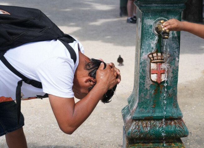 milan-italy-27th-june-2025-milan-hot-new-record-of-hot-in-milan-people-protect-themselves-from-the-sun-with-hats-umbrellas-in-the-shade-or-near-the-misting-fans-or-cooling-off-in-the-fountai