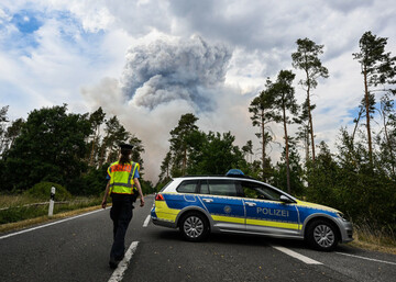 zeithain-germany-24th-june-2022-a-police-car-blocks-off-the-road-in-a-forest-fire-area-in-gohrischheide-in-gohrischheide-on-the-state-border-with-brandenburg-a-forest-area-contaminated-with-ammu