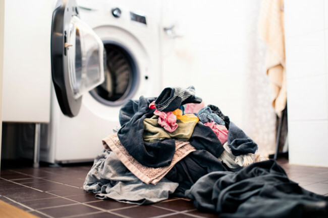 laundry-day-washing-machine-in-the-background-pile-of-dirty-clothes-on-the-floor-family-house-chores-and-domestic-work-concept-heap-of-socks