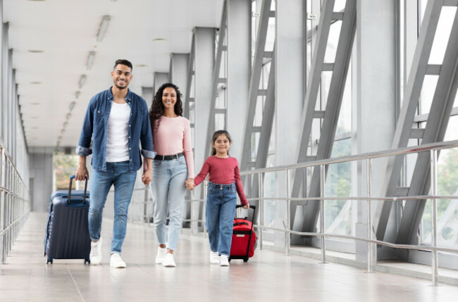 travel-insurance-smiling-arabic-family-with-daughter-walking-with-suitcases-at-airport